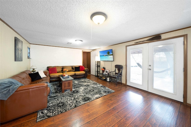 living room with a textured ceiling, crown molding, dark hardwood / wood-style flooring, and french doors