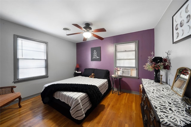 bedroom with hardwood / wood-style floors, multiple windows, and ceiling fan