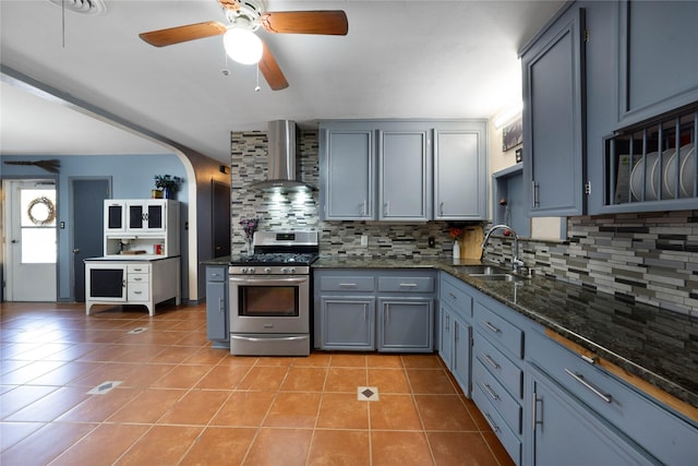 kitchen featuring gas stove, sink, wall chimney exhaust hood, backsplash, and light tile patterned flooring