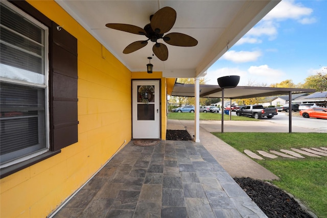 entrance to property featuring a carport, ceiling fan, and a lawn