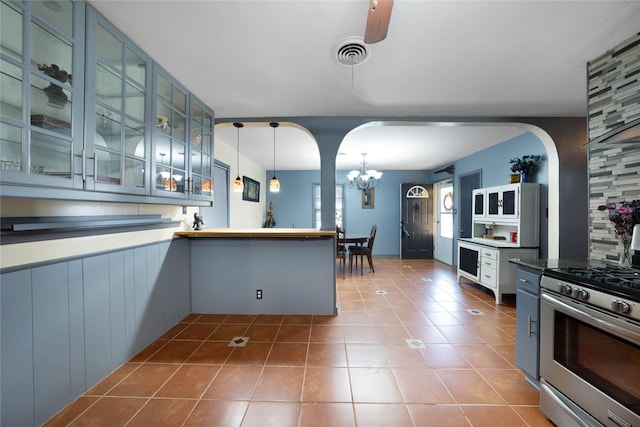 kitchen featuring pendant lighting, tile patterned floors, stainless steel gas stove, blue cabinetry, and a notable chandelier