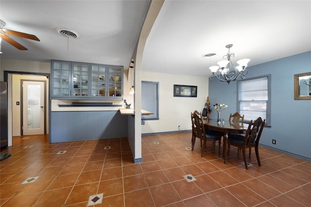 dining area with ceiling fan with notable chandelier and dark tile patterned flooring