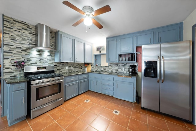 kitchen with ceiling fan, wall chimney exhaust hood, stainless steel appliances, blue cabinets, and backsplash