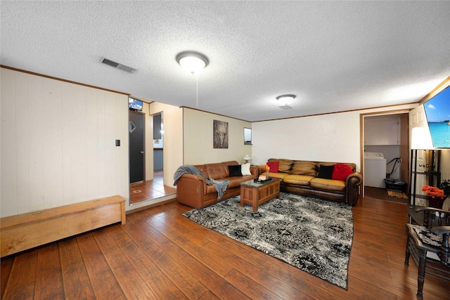 living room with dark hardwood / wood-style flooring, a textured ceiling, and washer / dryer