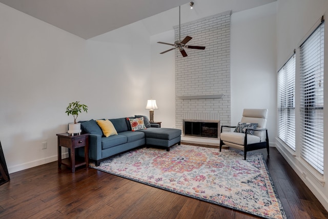 living room with dark hardwood / wood-style floors, a brick fireplace, a wealth of natural light, and ceiling fan