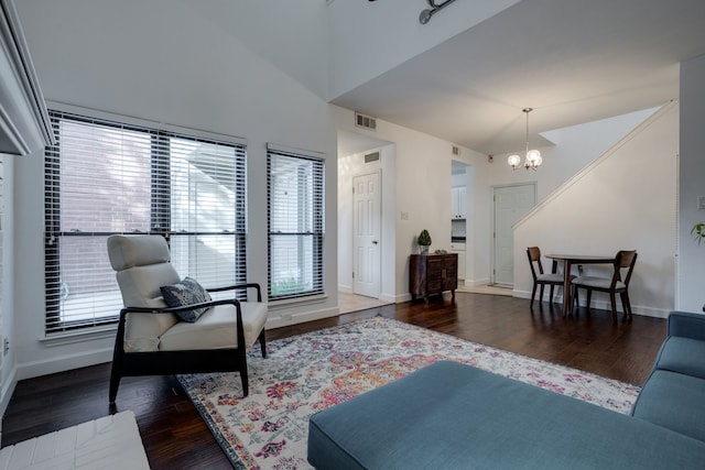 living room featuring dark hardwood / wood-style flooring, lofted ceiling, and an inviting chandelier