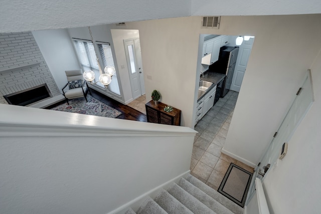 stairway featuring a fireplace, tile patterned flooring, and sink