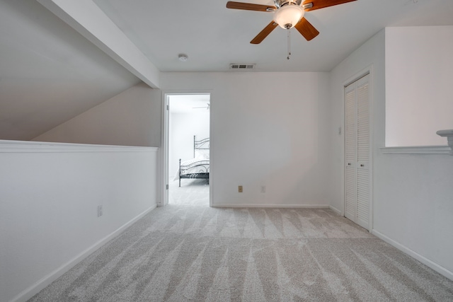 additional living space with lofted ceiling with beams, ceiling fan, and light carpet