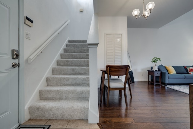 stairway with wood-type flooring and a chandelier