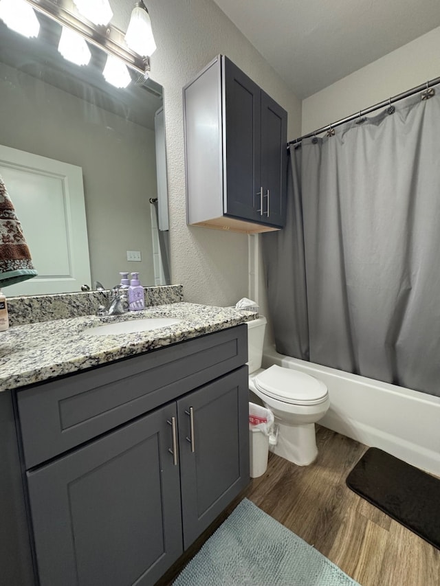 full bathroom featuring wood-type flooring, shower / tub combo, vanity, and toilet