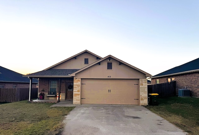 view of front of home with central AC, a yard, and a garage