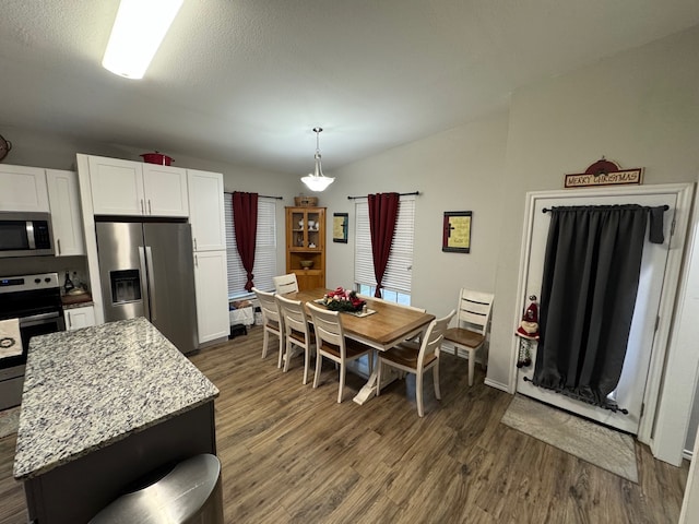 kitchen with a kitchen island, white cabinets, hanging light fixtures, light stone counters, and stainless steel appliances