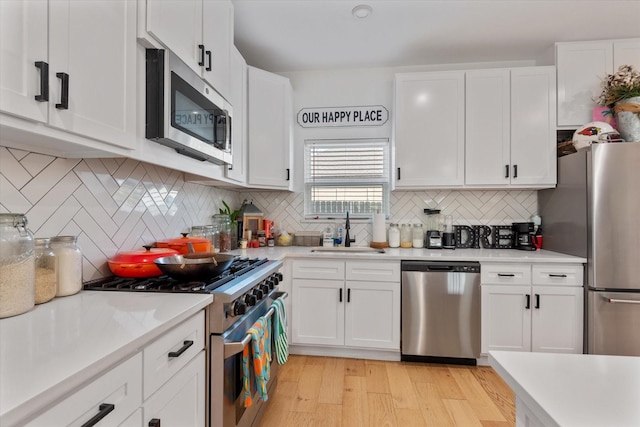 kitchen featuring sink, stainless steel appliances, light hardwood / wood-style floors, white cabinets, and decorative backsplash