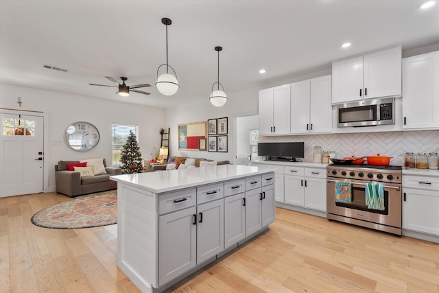 kitchen with white cabinetry, tasteful backsplash, decorative light fixtures, stainless steel appliances, and light hardwood / wood-style floors