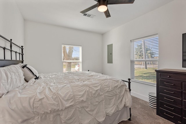 carpeted bedroom featuring ceiling fan, electric panel, and multiple windows