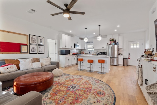 living room featuring ceiling fan, a wealth of natural light, and light hardwood / wood-style floors