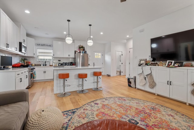 kitchen featuring pendant lighting, tasteful backsplash, white cabinetry, a center island, and stainless steel appliances