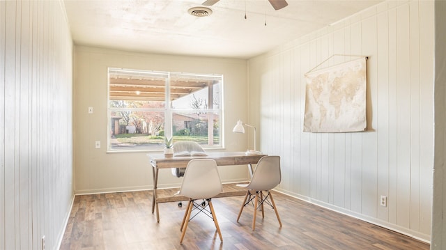 office with hardwood / wood-style floors, ceiling fan, and wood walls