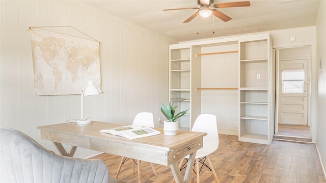 office area with hardwood / wood-style floors, ceiling fan, and wood walls