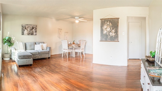 living room with dark hardwood / wood-style floors, ceiling fan, and a textured ceiling