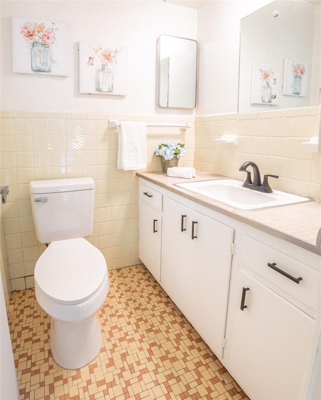 bathroom with vanity, toilet, and tile walls