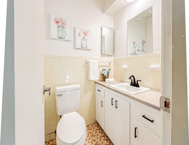 bathroom with vanity, tile walls, and toilet