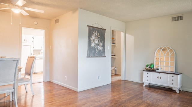 interior space featuring ceiling fan, a textured ceiling, and hardwood / wood-style flooring