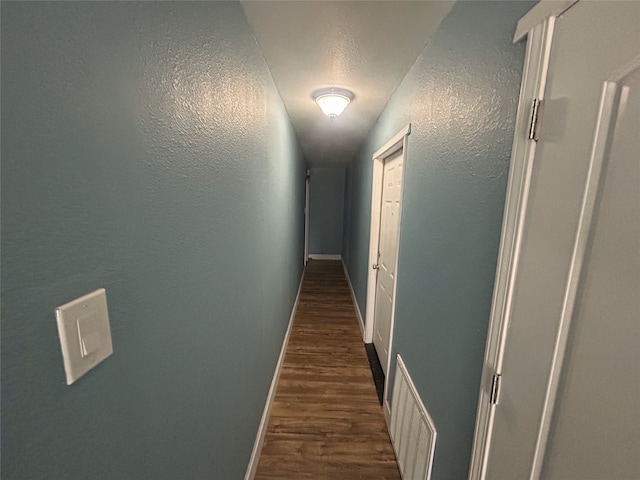 hallway with dark hardwood / wood-style floors and a textured ceiling