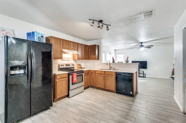 kitchen featuring light hardwood / wood-style flooring, black appliances, and a textured ceiling