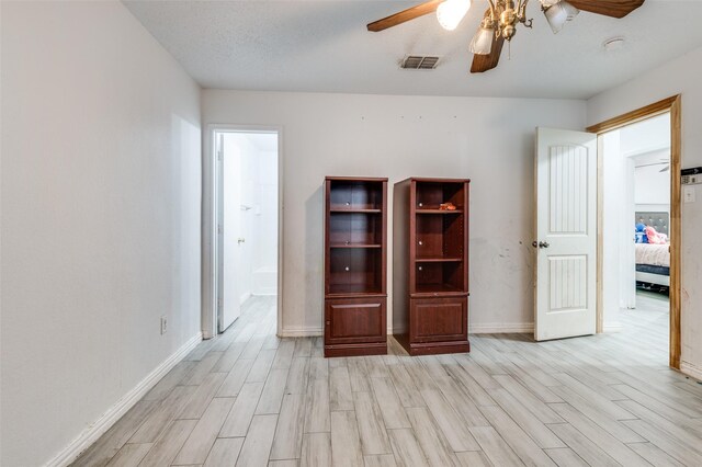 unfurnished room with ceiling fan, light wood-type flooring, and a textured ceiling