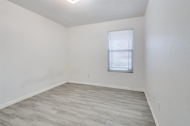 spare room with light wood-type flooring and a textured ceiling