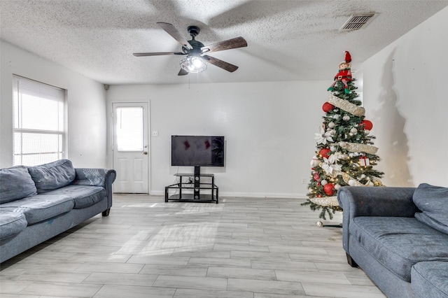 living room featuring light wood-type flooring, a textured ceiling, and ceiling fan