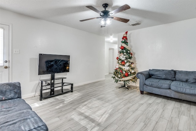 living room featuring ceiling fan, light hardwood / wood-style floors, and a textured ceiling