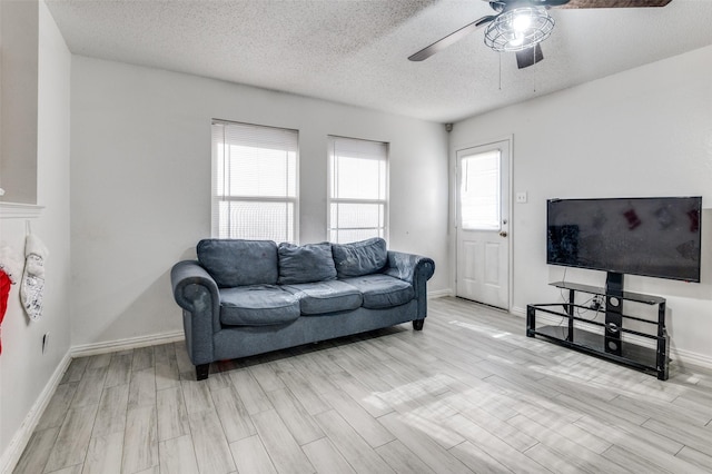 living room with a textured ceiling, light wood-type flooring, and ceiling fan