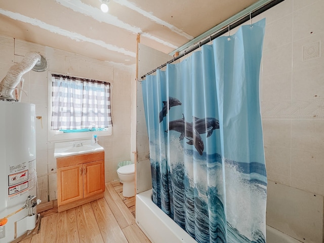 full bathroom featuring vanity, water heater, hardwood / wood-style flooring, tile walls, and toilet