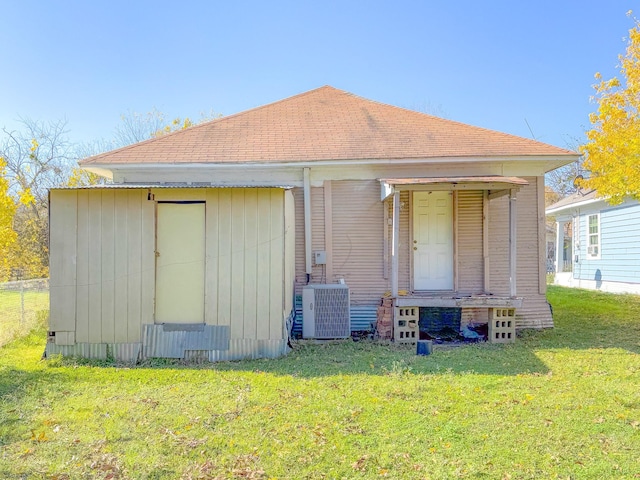 rear view of property with central air condition unit and a yard