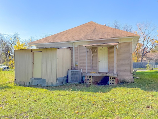 rear view of house featuring central AC unit and a lawn