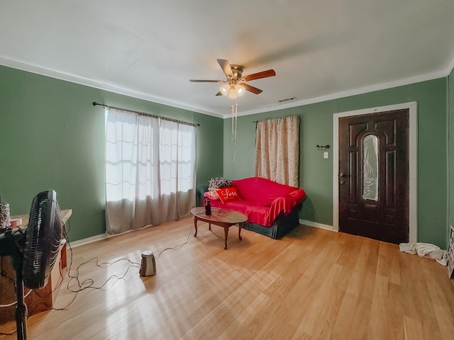 living area with ceiling fan, ornamental molding, and light hardwood / wood-style flooring