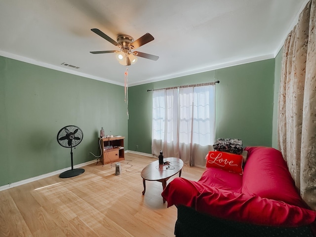 living area featuring wood-type flooring, ceiling fan, and ornamental molding