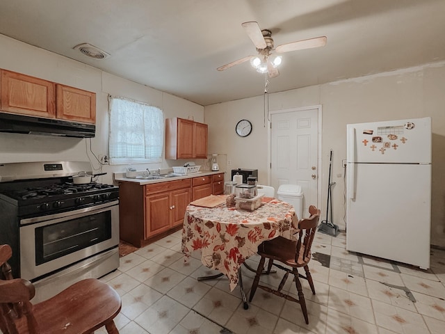 kitchen featuring stainless steel gas range oven, ceiling fan, sink, and white refrigerator