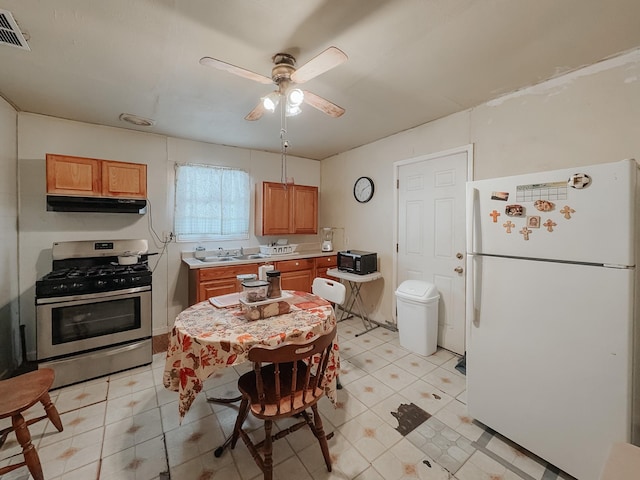 kitchen featuring stainless steel gas range oven, ceiling fan, sink, and white refrigerator