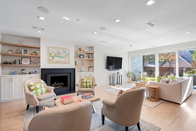 living room featuring built in features and light wood-type flooring