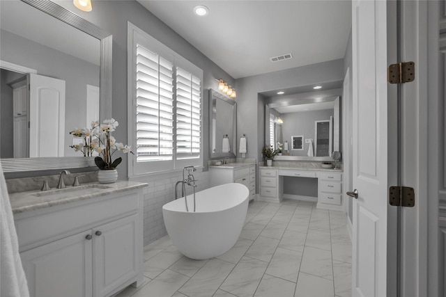 bathroom with vanity, tile walls, and a tub