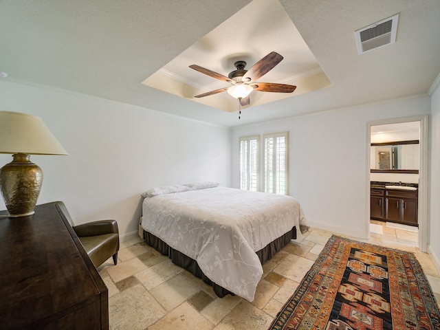 bedroom featuring ensuite bath, ceiling fan, sink, crown molding, and a tray ceiling