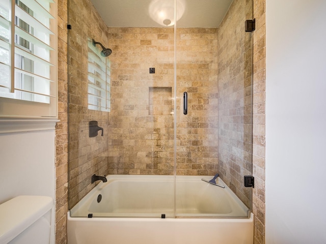 bathroom featuring shower / bath combination with glass door, toilet, and plenty of natural light