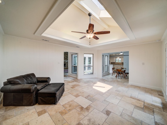 interior space with beam ceiling, a skylight, ceiling fan, wood walls, and a tray ceiling