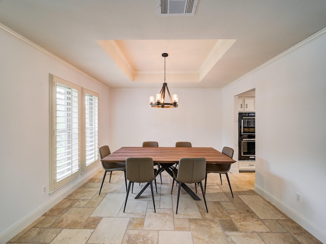 dining space with crown molding, a tray ceiling, and an inviting chandelier