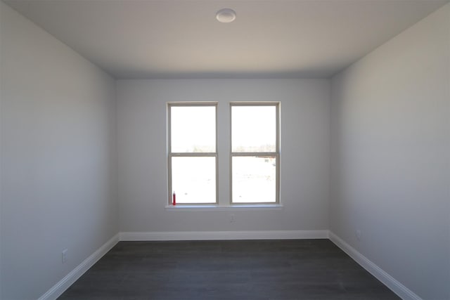 spare room with baseboards and dark wood finished floors