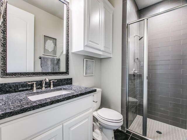 bathroom with tile patterned flooring, vanity, toilet, and a shower with shower door