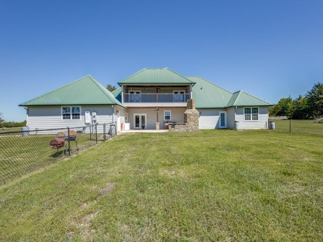 rear view of house with ceiling fan, a balcony, and a yard